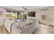 Bright living room featuring a gray sectional sofa, modern decor, wood-like flooring, and access to the backyard at 12430 Foxtail Run Ave, Las Vegas, NV 89138