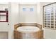 Elegant bathroom featuring an oval soaking tub with decorative tile surround, and a glass block window at 1252 Casa Palermo Cir, Henderson, NV 89011