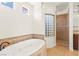 Bright bathroom features a luxurious soaking tub, glass block window, and a beautifully tiled walk-in shower at 1252 Casa Palermo Cir, Henderson, NV 89011