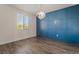 Bright bedroom features a modern chandelier, wood-look floors, a large window, and custom accent wall at 133 Clouded Ave, Henderson, NV 89002