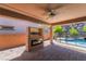 Covered patio area with outdoor fireplace, built-in television, and a view of the refreshing pool at 133 Clouded Ave, Henderson, NV 89002