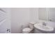 Powder room with white fixtures including a pedestal sink and low-flow toilet at 145 Aqua Commons Ln, Henderson, NV 89015