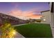 A cozy backyard with lush artificial turf, beautiful plants, and an appealing desert backdrop creating a serene outdoor space at 2004 Peaceful Mesa Ct, Henderson, NV 89052