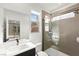 Bright bathroom featuring a modern vanity, tile shower with glass door, and a window providing natural light at 2004 Peaceful Mesa Ct, Henderson, NV 89052