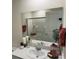 Bright bathroom with a modern white vanity and a large mirror reflecting the shower and a white door at 2534 Petunia Garden St # 222, North Las Vegas, NV 89081