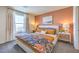 Bright bedroom featuring a queen bed, gray carpet, large window with curtains, and decorative nightstands at 2534 Petunia Garden St # 222, North Las Vegas, NV 89081