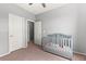 This carpeted bedroom has a grey baby crib and two white doors, and natural light through the window at 2672 Painted Mist Ct, Las Vegas, NV 89142