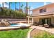 Inviting backyard with lush landscaping, covered patio seating, and a unique rock waterfall pool feature at 3341 Heavenly View Ct, Las Vegas, NV 89117
