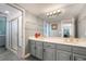 Bright bathroom featuring a double vanity with grey cabinets, granite countertop, and a glass-enclosed shower at 3341 Heavenly View Ct, Las Vegas, NV 89117