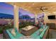 Inviting covered patio with a cozy seating area, fire pit, ceiling fan, and string lights for outdoor relaxation at 352 Dandelion Brook Ct, Las Vegas, NV 89148