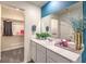 Bright bathroom featuring a white vanity, large mirror, and a walk-in closet for extra storage at 48344 Orchid Ridge Ave # 104, Las Vegas, NV 89141