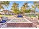 Beautiful outdoor space with brick pavers, fire pit, and comfortable seating areas surrounded by lush landscaping and buildings at 720 Webber Park St, Henderson, NV 89011
