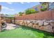 Well-maintained backyard featuring artificial turf, a rock wall, string lights and a gazebo at 7641 Lani Dawn St, Las Vegas, NV 89149