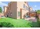 Spacious backyard features artificial grass, an outdoor kitchen, and stucco wall at 7641 Lani Dawn St, Las Vegas, NV 89149