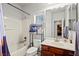 Bright bathroom featuring a cherry vanity, a shower-tub combo, and neutral wall color at 7641 Lani Dawn St, Las Vegas, NV 89149