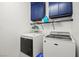 Functional laundry room with white appliances, blue cabinets, and storage shelves at 7641 Lani Dawn St, Las Vegas, NV 89149