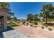 Backyard view with mature trees, desert landscaping, golf course view, and covered patio at 9520 Sundial Dr, Las Vegas, NV 89134
