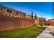 Backyard with artificial turf, tall brick wall, and string lights to create a relaxing and private oasis at 10047 Alden Creek St, Las Vegas, NV 89141