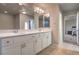 Well-lit bathroom featuring double sinks with a white cabinet and two large mirrors at 10047 Alden Creek St, Las Vegas, NV 89141