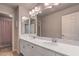 Bright bathroom featuring dual sinks with a large mirror, ample counter space, and a separate room for the toilet and shower at 10047 Alden Creek St, Las Vegas, NV 89141
