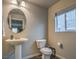 This cozy bathroom features a sleek pedestal sink and toilet next to a window, providing a simple yet elegant space at 10047 Alden Creek St, Las Vegas, NV 89141