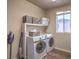 Well-lit laundry room with modern washer and dryer, plus ample storage space above at 10047 Alden Creek St, Las Vegas, NV 89141