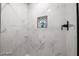 Sleek shower with white marble-style tile, dark hardware, and built in shelf at 1012 Greystone Dr, Las Vegas, NV 89108