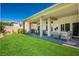 Expansive backyard with a covered patio, outdoor kitchen, and lush green lawn at 10301 Bent Brook Pl, Las Vegas, NV 89134