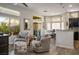 Open-concept living room with neutral tones, comfortable seating, and sliding door access to the patio at 10301 Bent Brook Pl, Las Vegas, NV 89134