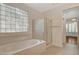Bright bathroom features a shower and separate tub, a glass block window, and neutral tile at 10302 Cara Mia Ct, Las Vegas, NV 89135