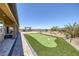 Wide shot of backyard with putting green, barbecue, pool, desert landscaping, and covered patio at 11088 Westcroft Way, Las Vegas, NV 89183