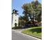 Community entrance featuring a tower, green lawns, mature trees, and covered walkways at 2100 Plaza Del Padre, Las Vegas, NV 89102