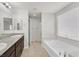 Bright bathroom featuring double sinks, granite countertops, a soaking tub, and a window at 2228 Sky Island Dr, Henderson, NV 89002