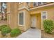 Close-up of a condo entrance featuring a white door, stucco exterior, and manicured shrubs at 251 S Green Valley Pkwy # 1311, Henderson, NV 89012