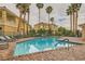 Relaxing community pool surrounded by palm trees and lounge chairs on a brick patio at 251 S Green Valley Pkwy # 1311, Henderson, NV 89012