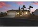 Exterior view of a single-story home with a three car garage, desert landscaping and sunset sky at 2612 Dearport Ct, Henderson, NV 89052
