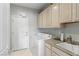 Bright laundry room with built-in cabinets, utility sink, and modern appliances at 2612 Dearport Ct, Henderson, NV 89052
