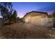 Backyard at dusk with desert landscaping, covered patio, and hardscape at 3521 Discovery Downs Ct, North Las Vegas, NV 89081