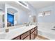 Bright bathroom featuring a tub, walk-in shower, double sink, and a large mirror at 452 Waterwheel Falls Dr, Henderson, NV 89015