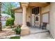 Inviting front porch with decorative glass door, accent chairs and manicured landscaping at 5449 Desert Spring Rd, Las Vegas, NV 89149