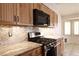 Close up on gas range and microwave featuring wood cabinets and stone countertops at 6016 Bungalow Bay St, Las Vegas, NV 89130