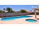 Large pool and hot tub with mature palm trees and sunny sky at 6016 Bungalow Bay St, Las Vegas, NV 89130