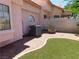 Outdoor view of HVAC system along side of home with artificial lawn and rock ground cover at 613 Cervantes Dr, Henderson, NV 89014