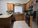 Kitchen featuring wood cabinets, granite countertops, stainless steel appliances and tiled flooring at 6361 Copperfield Ave, Las Vegas, NV 89108