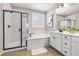 This bathroom features a shower with black trim, soaking tub, and bright vanity with wood-look tile at 6611 Dove Point Pl, Las Vegas, NV 89130