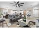Bright living room with tile floors, modern furniture, ceiling fan, and open layout to the kitchen and dining area at 6611 Dove Point Pl, Las Vegas, NV 89130
