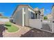 View of backyard with faux grass and rock landscaping with a white fence and gate at 6844 Tropicaire St, Las Vegas, NV 89149