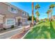 Inviting two-story townhouse featuring lush green lawn, mature palm trees, and a charming front entrance at 76 Stock Option St # 2, Henderson, NV 89074
