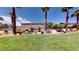 Exterior view of townhouses featuring a well-manicured lawn and mature palm trees at 76 Stock Option St # 2, Henderson, NV 89074