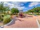 Community playground featuring slides, climbing structures, and soft ground cover, surrounded by trees at 76 Stock Option St # 2, Henderson, NV 89074